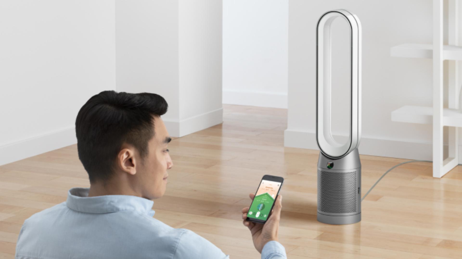 A man controls his Dyson Purifier Cool TP07 purifying fan using the MyDyson app.